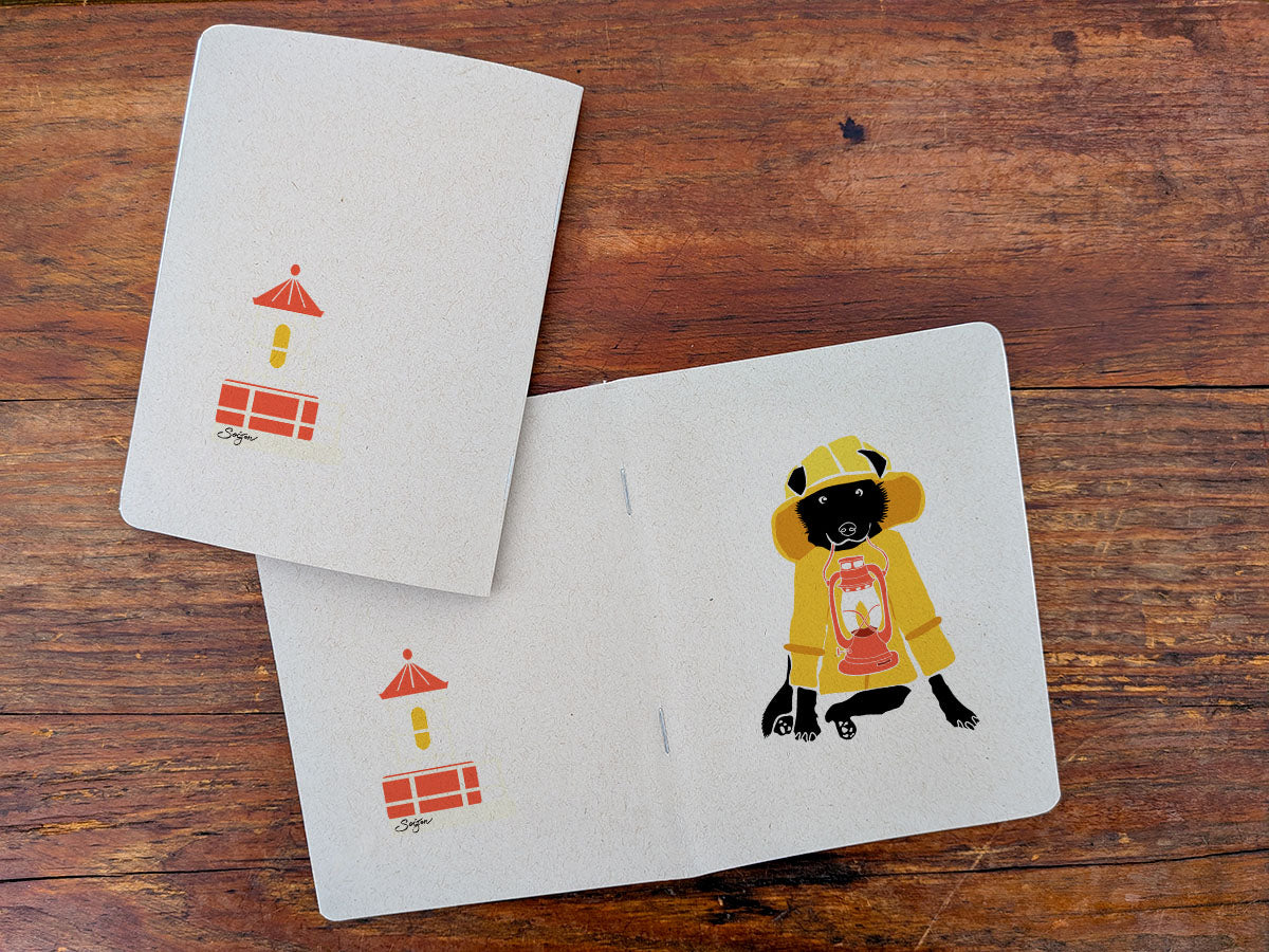 Notebook with dog in yellow jacket holding a lantern illustration on a wood surface.