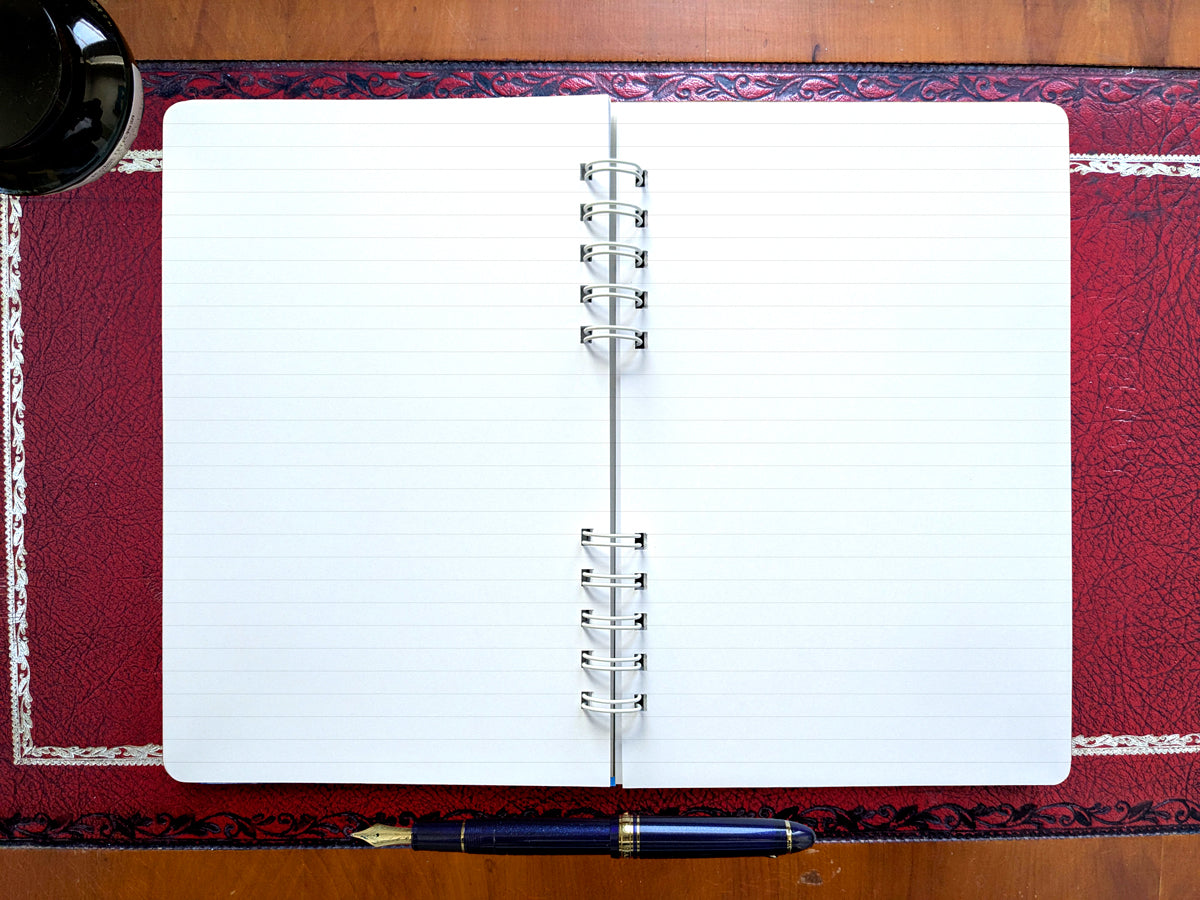 Open lined notebook with a pen on a decorative surface