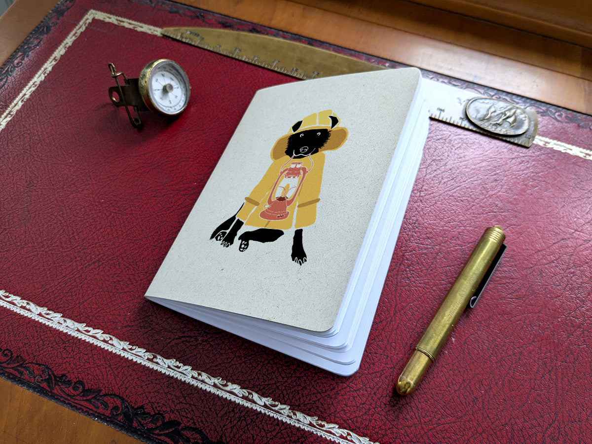 Notebook with dog in yellow jacket holding a lantern illustration on a red surface with a pen and small compass.