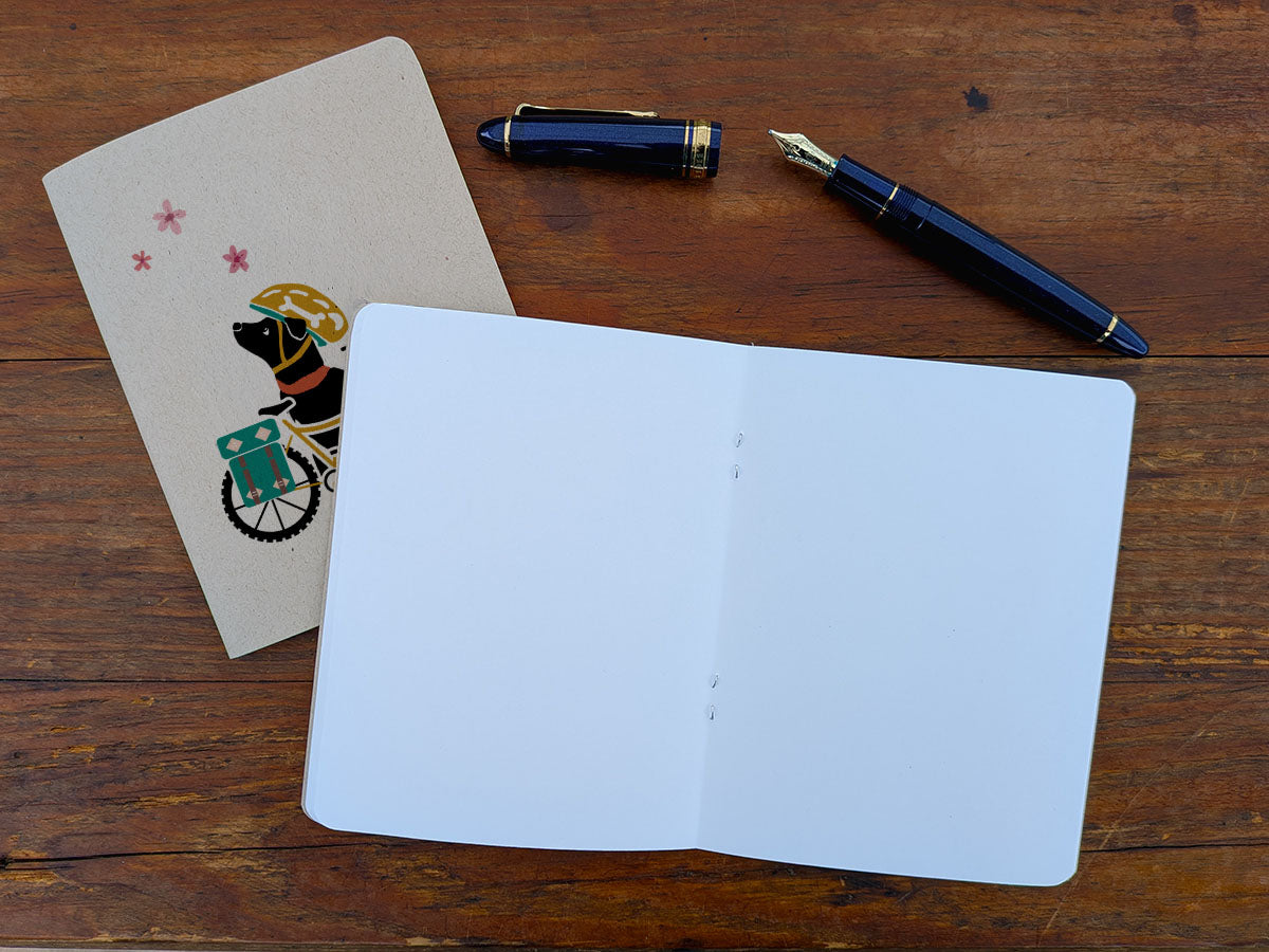 Open blank notebook with a pen and a pen on a wooden surface