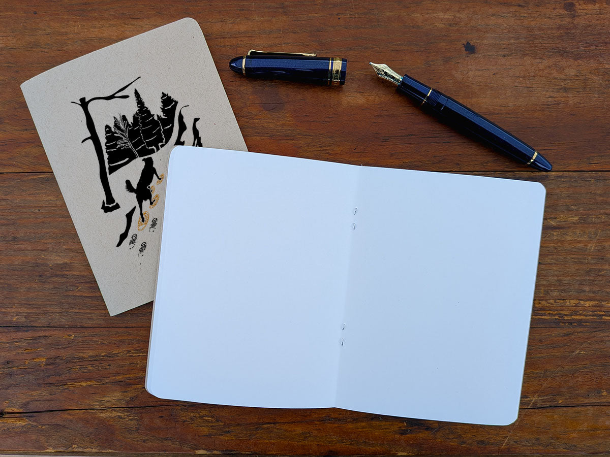 Open blank notebook with a pen and a pen on a wooden surface