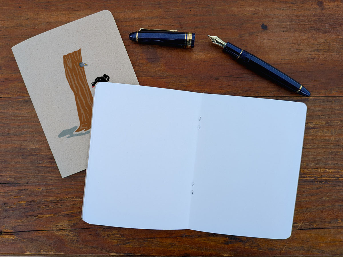 Open blank notebook with a pen and a pen on a wooden surface