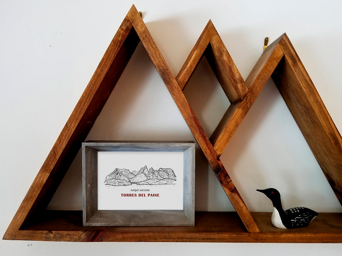 Framed art print on wooden shelf of black and white mountains and the text Parque Nacional Torres del Paine