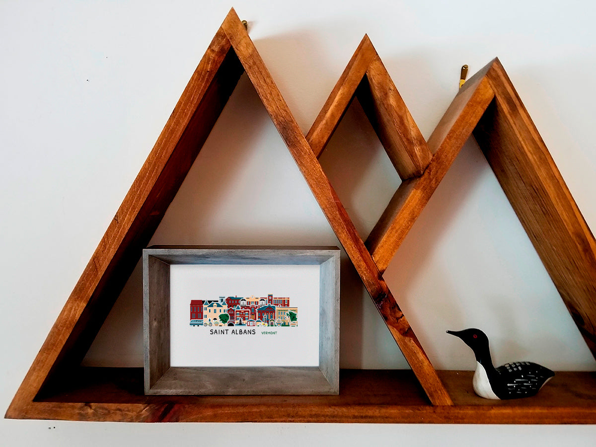 Framed print featuring buildings of Saint Albans Vermont arranged in a cityscape on a wooden shelf