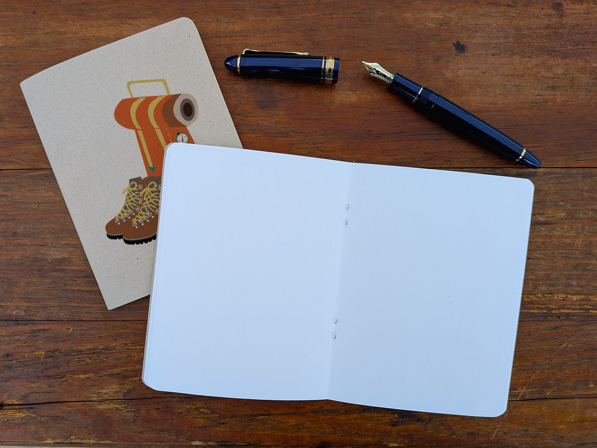 Open blank notebook with a pen and a pen on a wooden surface