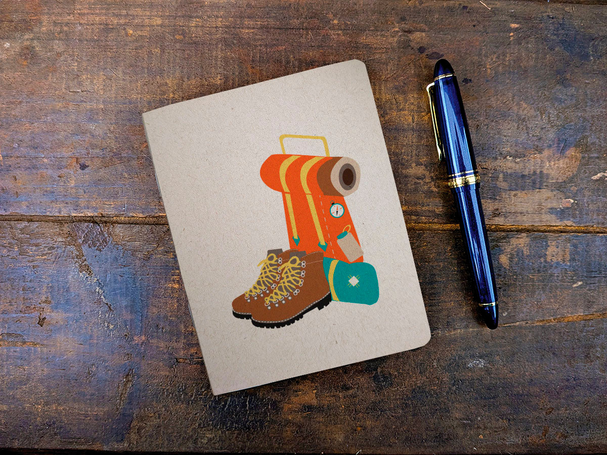 Notebook with a backpacking pack and boot illustration and a pen on a wooden surface