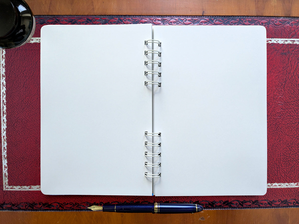 Open notebook with blank pages on a red desk.