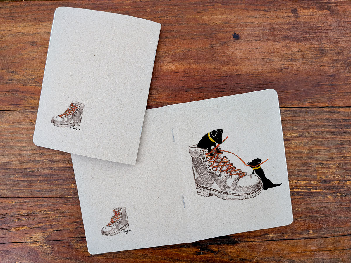 Two notebooks with dog with hiking boot illustration on a wooden surface