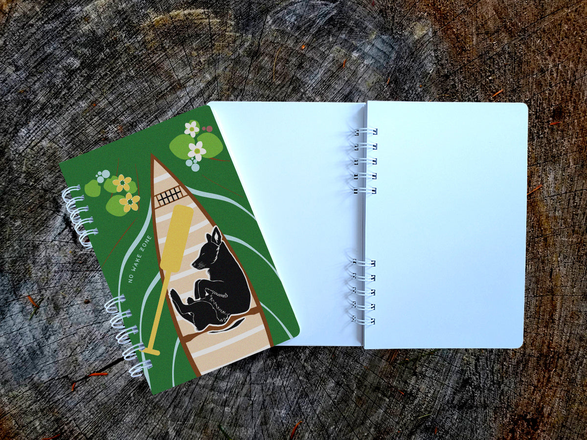 Notebook with illustration of dog sleeping in a canoe with text No Wake Zone.