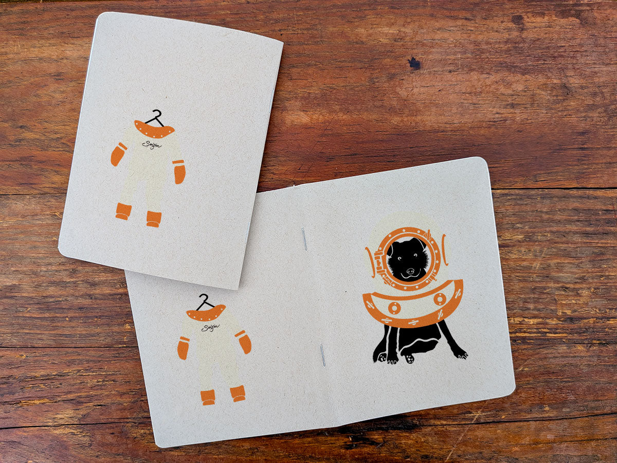 Notebooks with dog with diving helmet illustration on a wood surface.